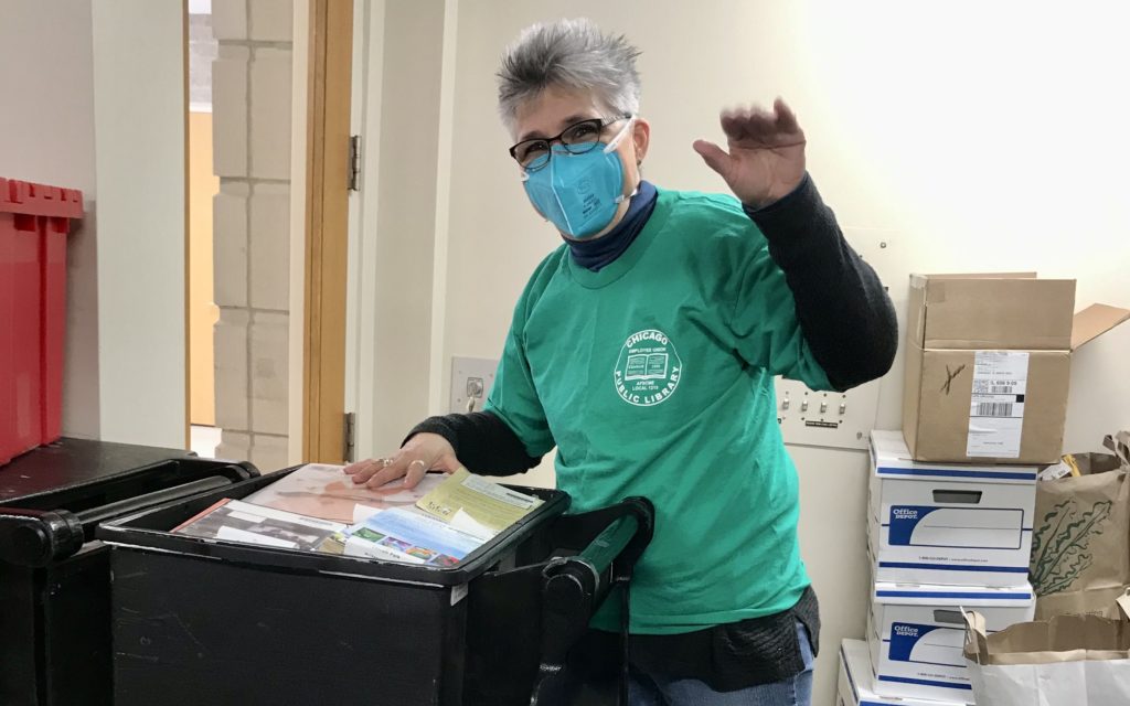 A union member raises a fist in solidarity while using a book cart.