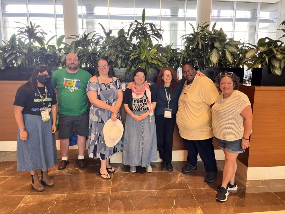 Local 1215's 2024 international convention delegates post in front of plants.