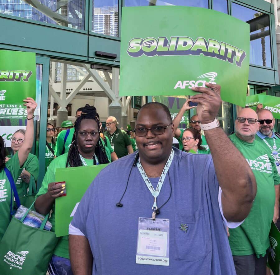 Member Allen holds up a "Solidarity" sign outside at a rally.