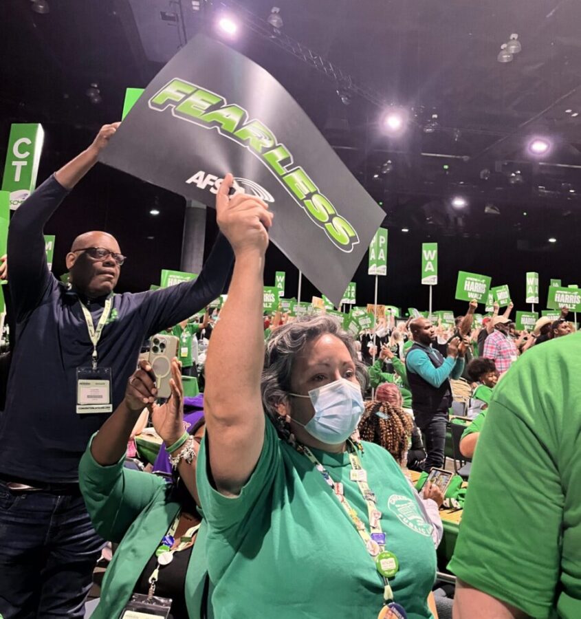 AFSCME members hold up signs on the convention floor.